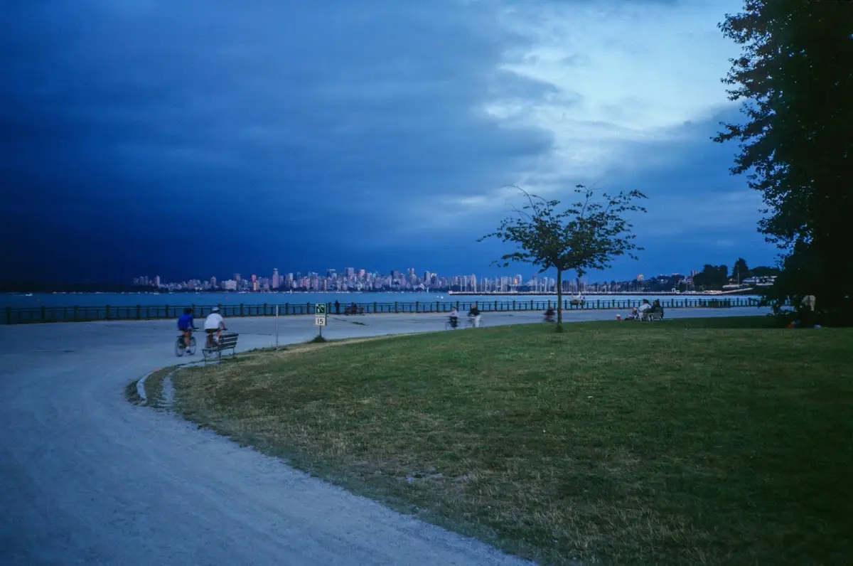 Radweg am Wasser mit der Skyline von Vancouver im Hintergrund unter dunklen Wolken