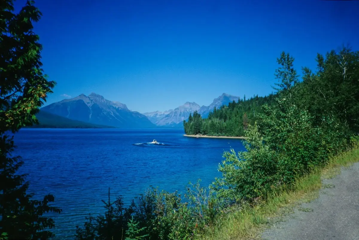 Blauer Bergsee im Glacier National Park mit Booten, dahinter Gipfel