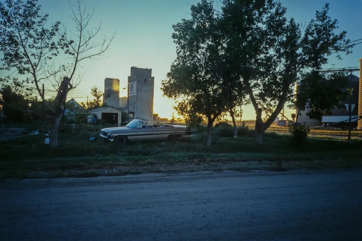 Getreidesilos und ein altes Auto am Ortsrand im Abendlicht