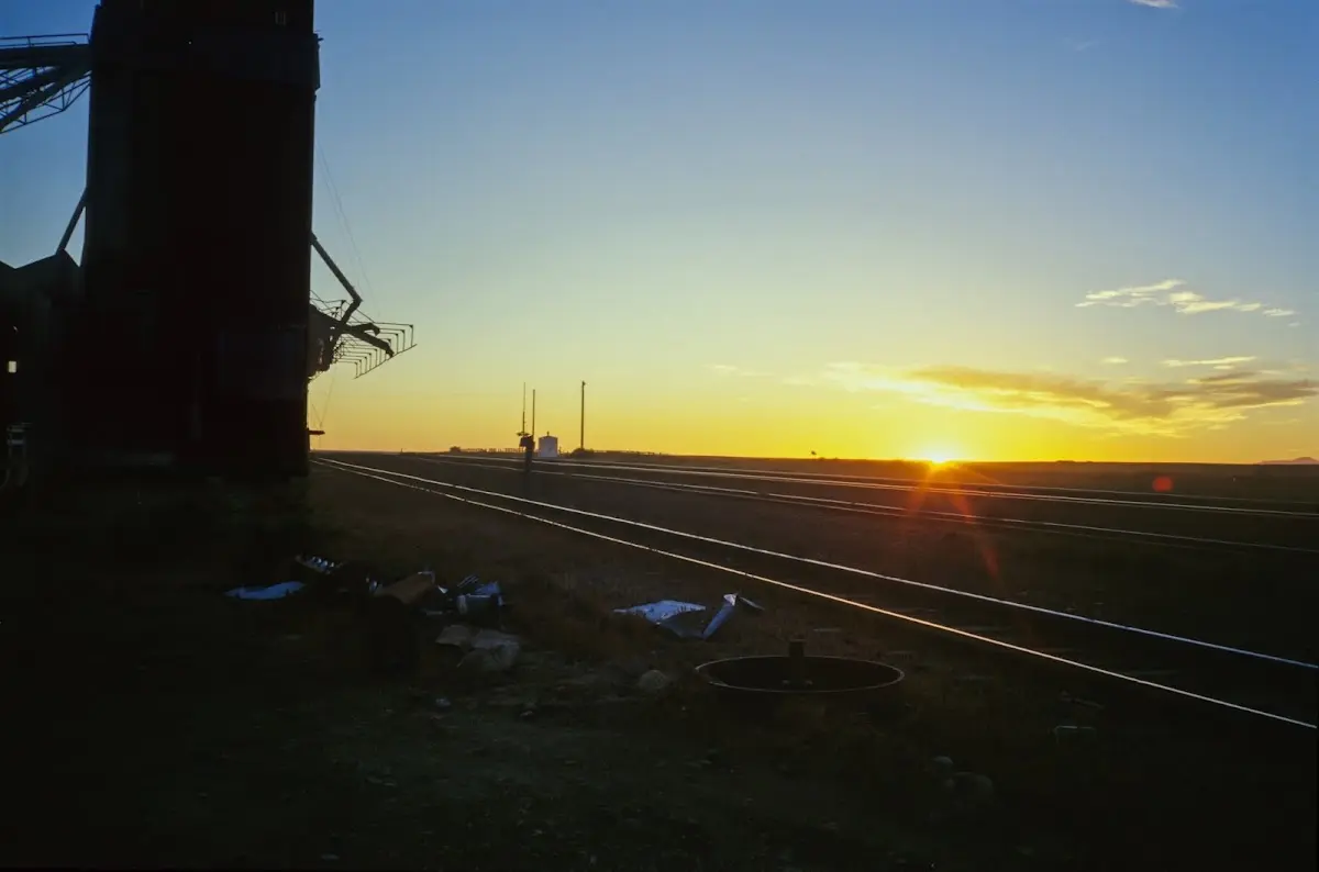 Sonnenuntergang über Bahngleisen neben einem großen Getreidesilo