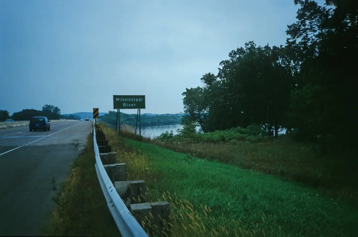 Straße mit Leitplanke am Mississippi, am Rand das Schild Mississippi River