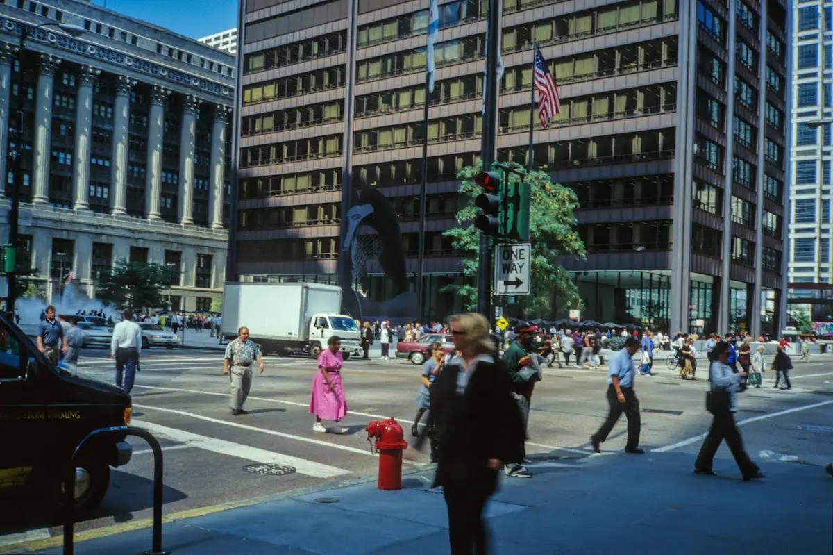 Fußgänger an einer Kreuzung in der Innenstadt von Chicago, Bürohochhäuser und US-Flagge