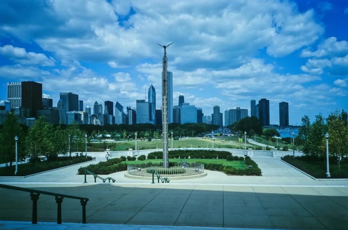 Park mit Obelisk und Brunnen vor der Skyline von Chicago unter Wolken