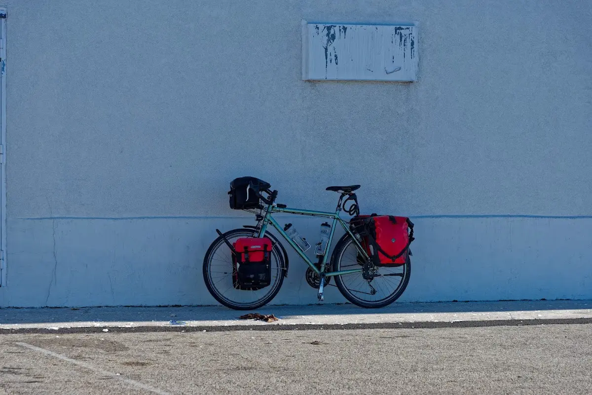 Reiserad mit roten Packtaschen an einer Hauswand